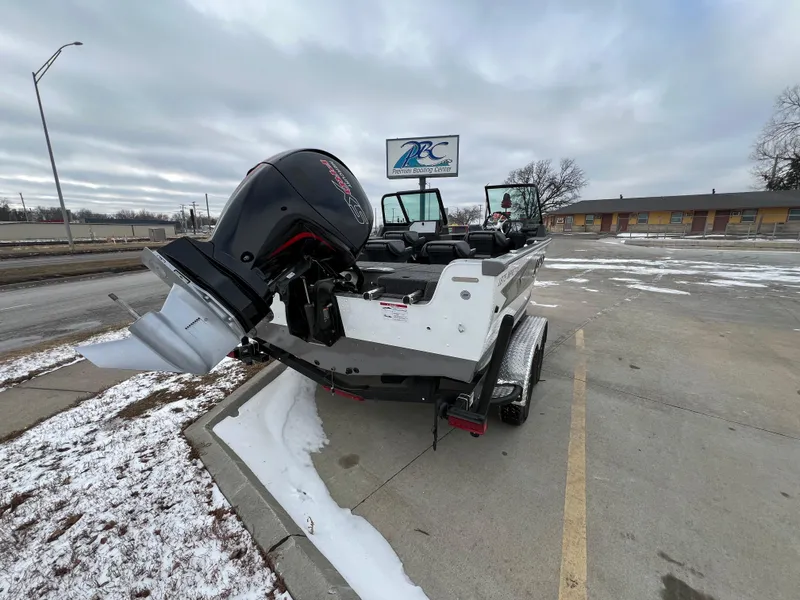 Slide: The Image of 2025 Lund 1875 Impact XS Sport boat on trailer in snowy parking lot. - 6