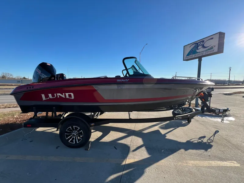 Slide: The Image of 2025 Lund 189 Pro-V GL boat on trailer, parked outdoors under clear sky. - 0