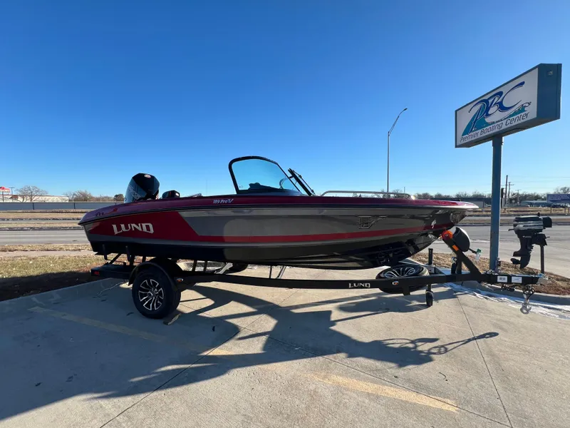 Slide: The Image of 2025 Lund 189 Pro-V GL boat on trailer, parked outdoors under clear sky. - 1
