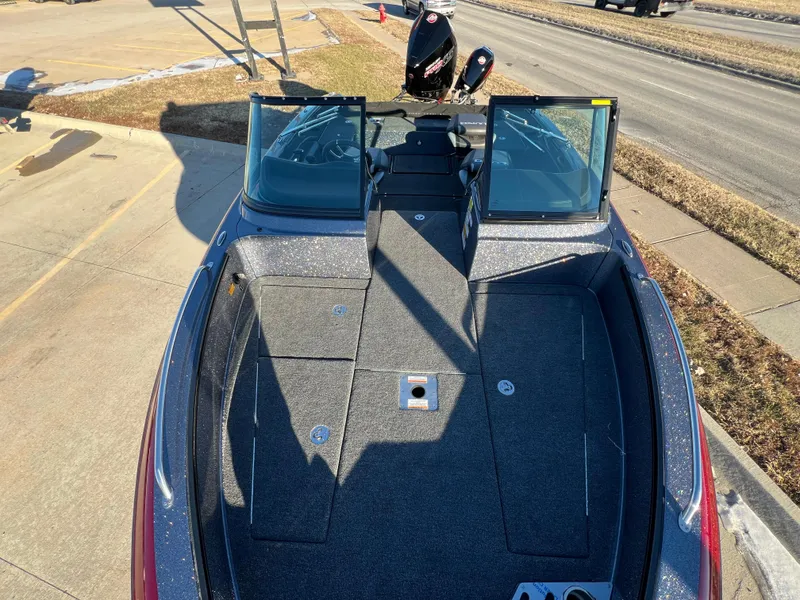 Slide: The Image of 2025 Lund 189 Pro-V GL boat with open deck and windshield, parked outdoors. - 23