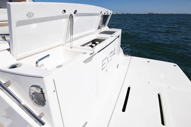 Slide: The Image of 2025 Tiara Yachts EX 54 yacht deck with open storage compartments on the ocean. - 14