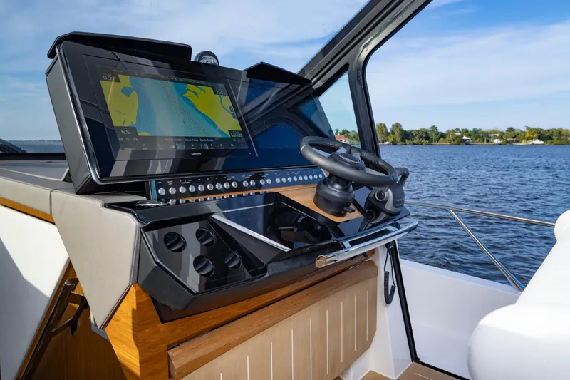 Slide: The Image of 2025 Tiara Yachts EX 54 helm with navigation display on a serene lake. - 33
