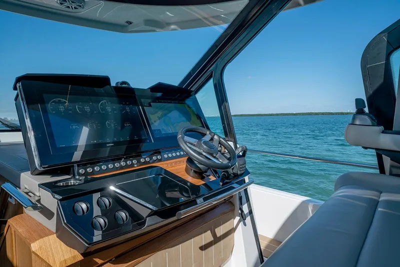 Slide: The Image of 2025 Tiara Yachts EX 60 helm with advanced navigation system, steering wheel, and ocean view. - 32