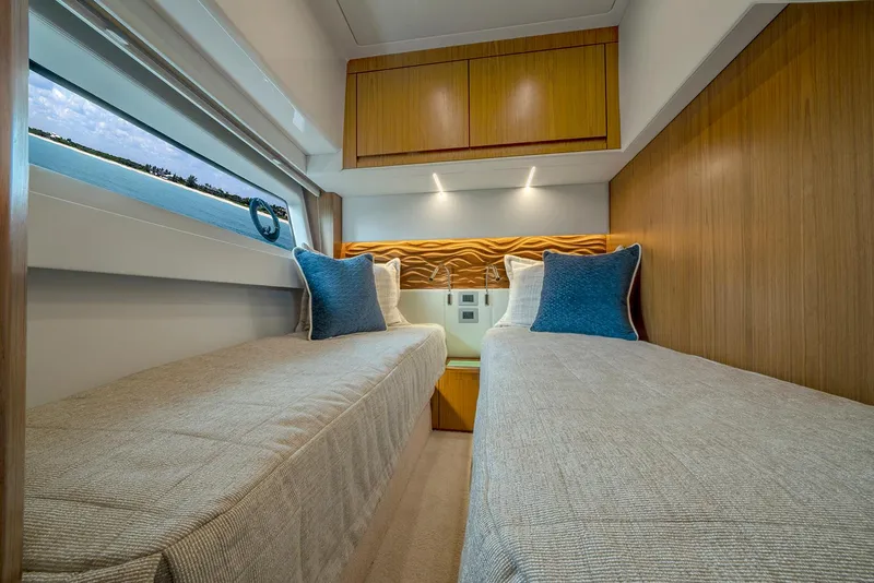 Slide: The Image of 2025 Tiara Yachts EX 60 cabin with twin beds and modern wood accents. - 44