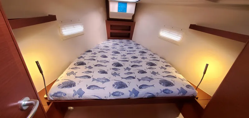 Slide: The Image of 2024 Hanse 388 yacht cabin with fish-patterned bedding and warm lighting. - 14