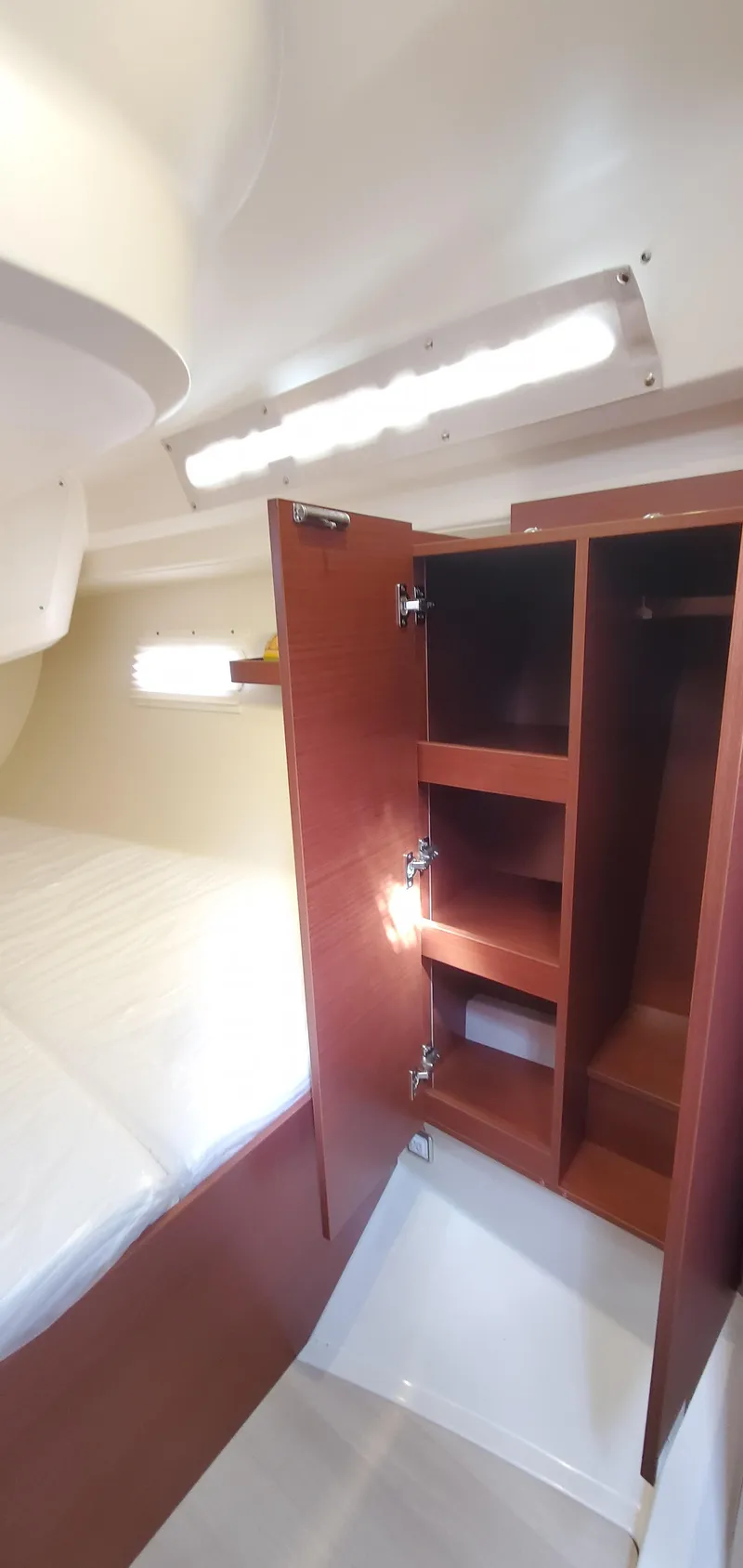 Slide: The Image of 2024 Hanse 388 yacht interior with open wooden cabinet and bed. - 27