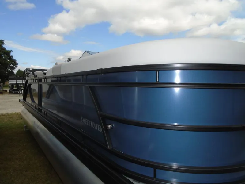 Slide: The Image of 2025 Godfrey Sweetwater 2286 SB pontoon boat with blue exterior under a cloudy sky. - 19