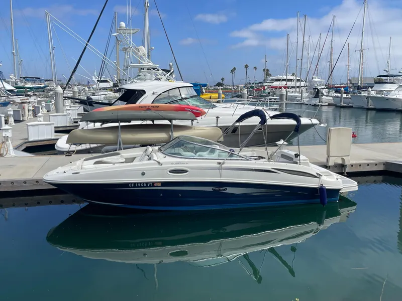 Slide: The Image of 2010 Sea Ray 260 Sundeck docked in a marina with sailboats in the background. - 1