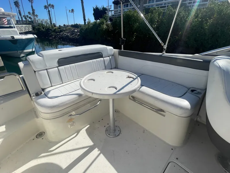 Slide: The Image of 2010 Sea Ray 260 Sundeck boat interior with seating and table, sunny day. - 11