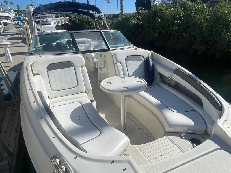 Slide: The Image of 2010 Sea Ray 260 Sundeck boat with spacious seating and table, docked in a marina. - 2