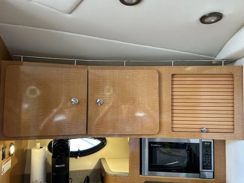 Slide: The Image of 2010 Larson Cabrio 370 interior kitchen with wooden cabinets and microwave. - 21
