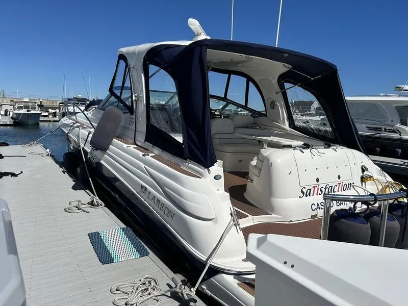 Slide: The Image of 2010 Larson Cabrio 370 boat docked at marina, featuring sleek design and covered cockpit. - 26