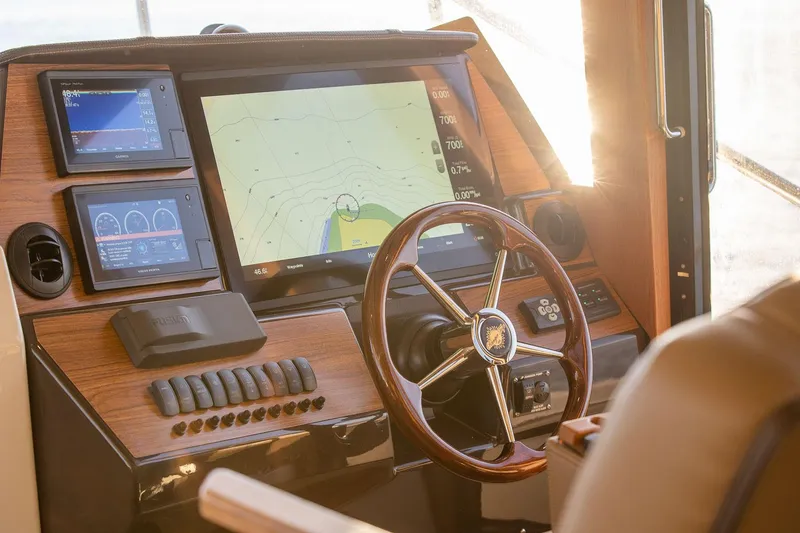 Slide: The Image of 2025 Ranger Tugs R-43 S helm with navigation screens and wooden steering wheel. - 19