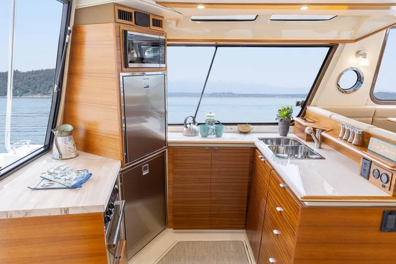 Slide: The Image of Luxurious 2025 Ranger Tugs R-43 S yacht kitchen with modern appliances and scenic ocean view. - 6