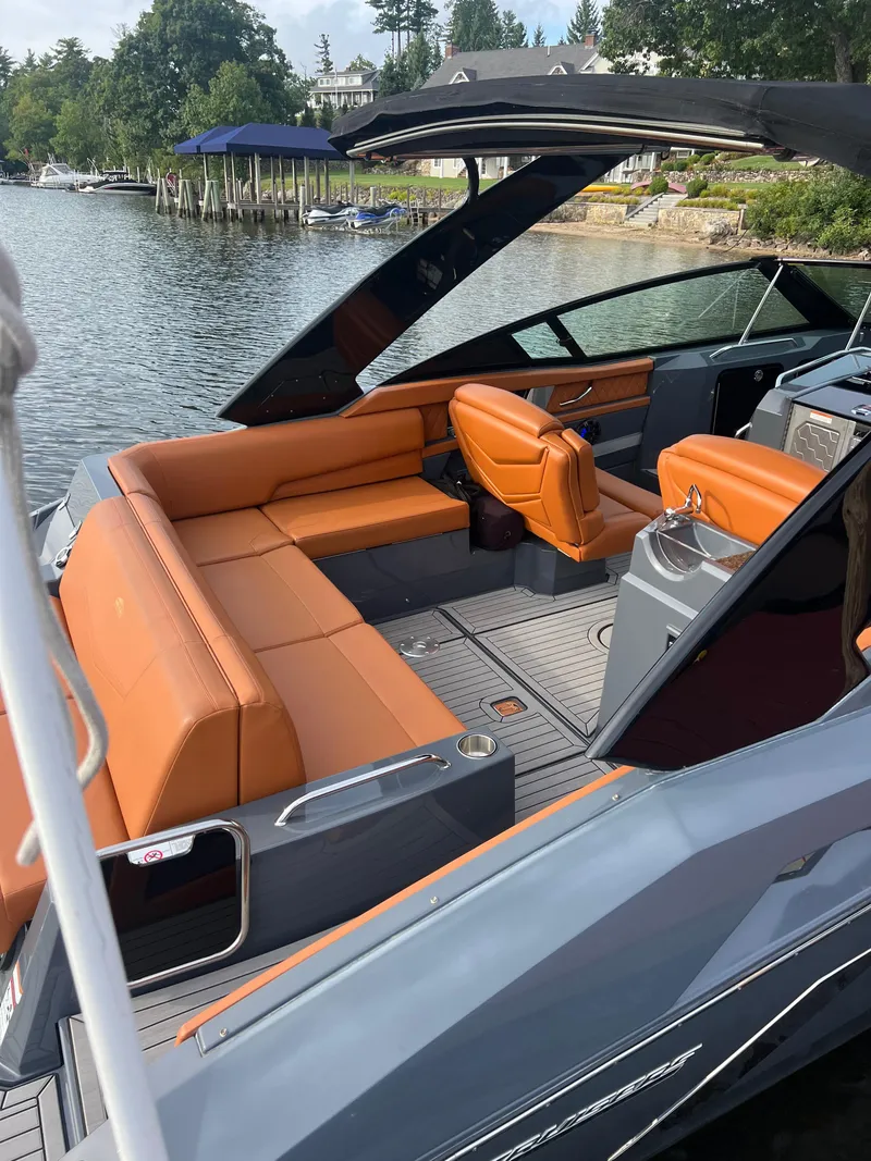Slide: The Image of 2016 Cruisers Yachts 338 SOUTH BEACH with orange seating, docked by a scenic lakeside. - 5