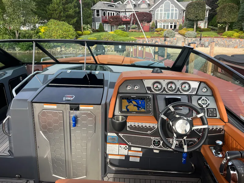 Slide: The Image of 2016 Cruisers Yachts 338 SOUTH BEACH dashboard with navigation system and controls, docked near a house. - 9