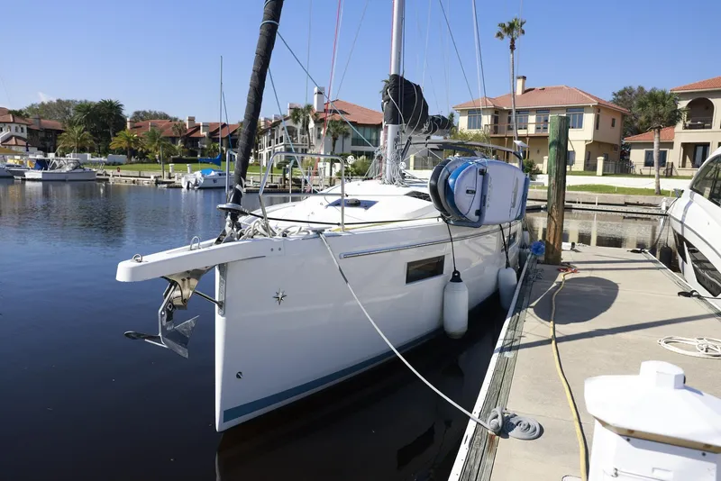 The Image of 2022 Jeanneau Sun Odyssey 410 docked in a marina, surrounded by waterfront homes. - 0