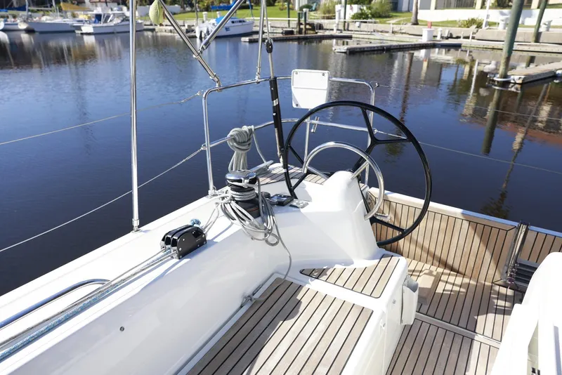 Slide: The Image of 2022 Jeanneau Sun Odyssey 410 sailboat cockpit with steering wheel and marina view. - 2