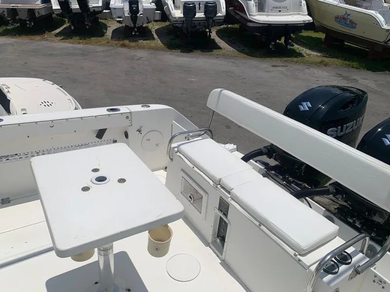 Slide: The Image of 2000 Robalo 2640 Walkaround boat interior with seating and table, parked with other boats. - 18