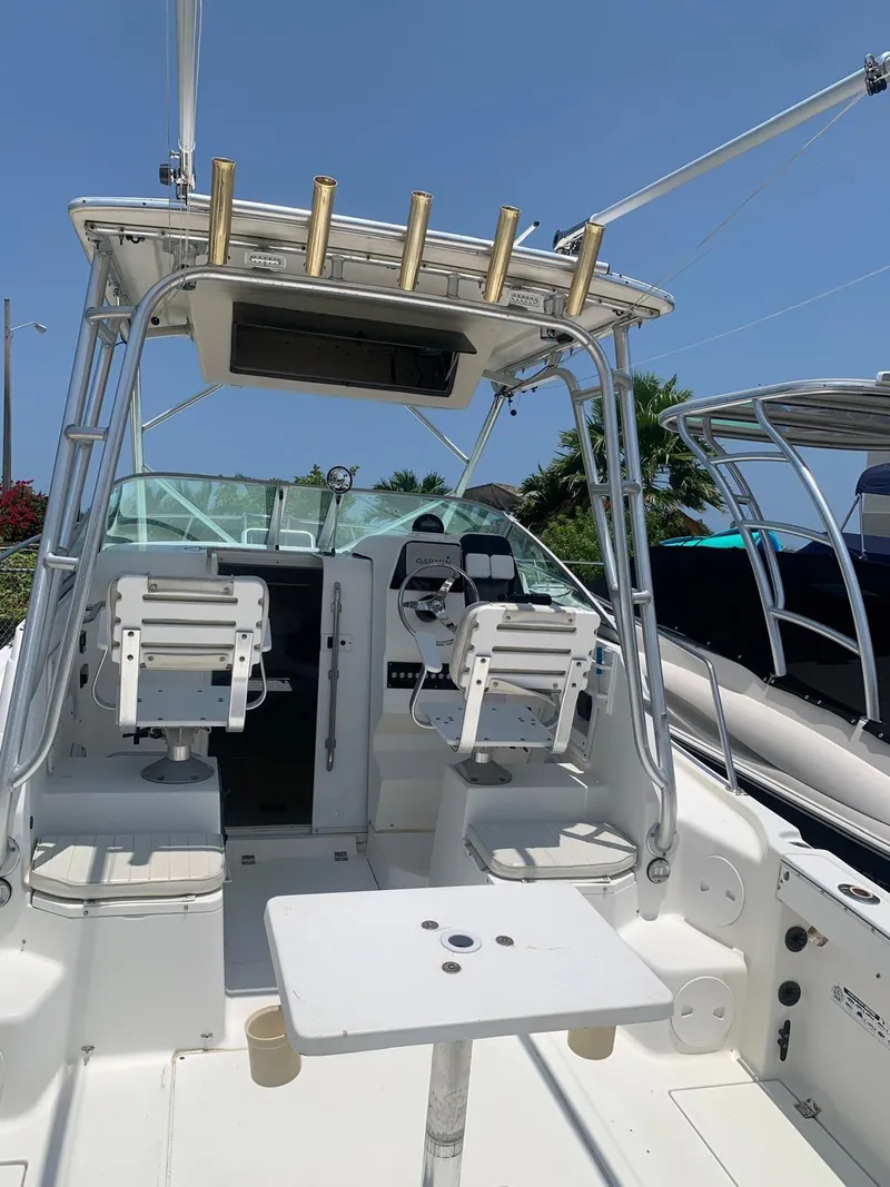 Slide: The Image of 2000 Robalo 2640 Walkaround boat interior with seating and helm under clear blue sky. - 22