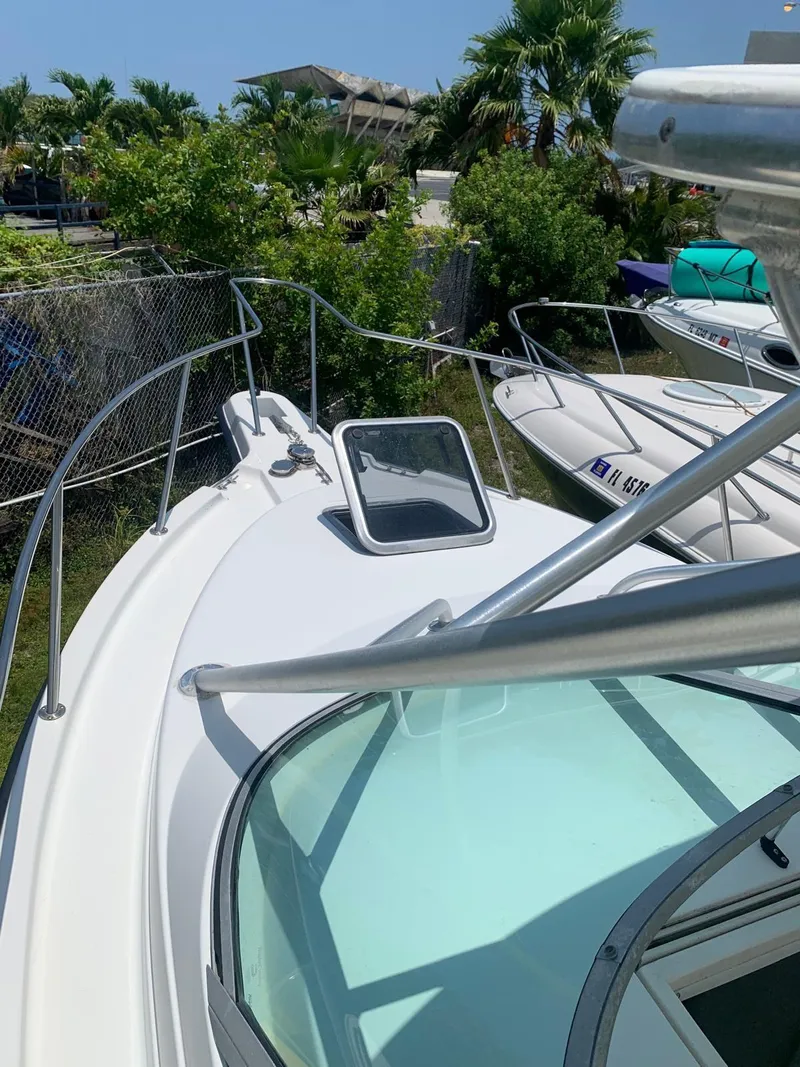 Slide: The Image of 2000 Robalo 2640 Walkaround boat with open hatch, docked near lush greenery. - 25