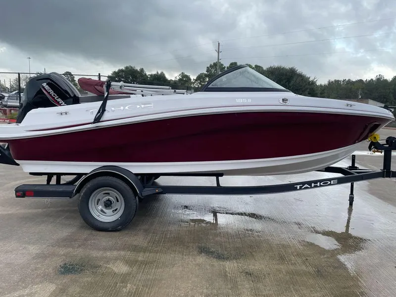 Slide: The Image of 2024 Tahoe 185 S boat on trailer, maroon and white, parked outdoors. - 1
