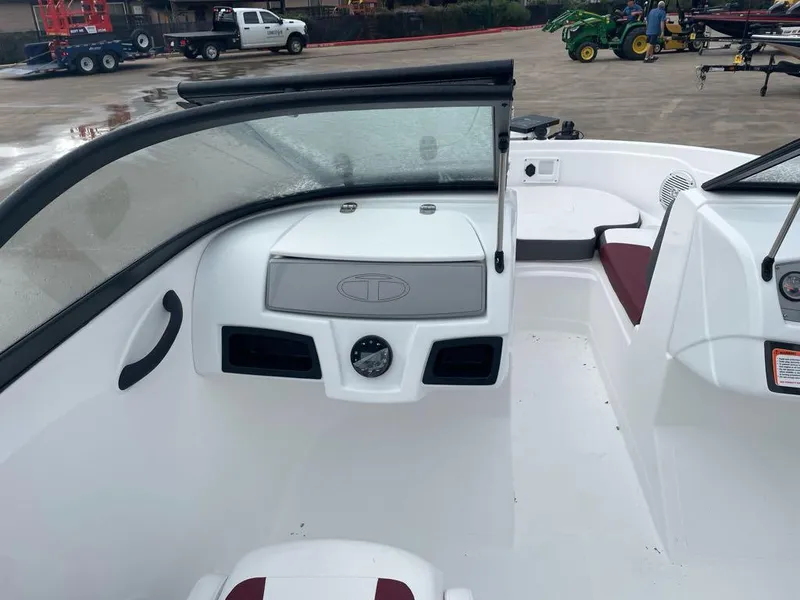 Slide: The Image of 2024 Tahoe 185 S boat interior with windshield and seating, parked on a concrete lot. - 5