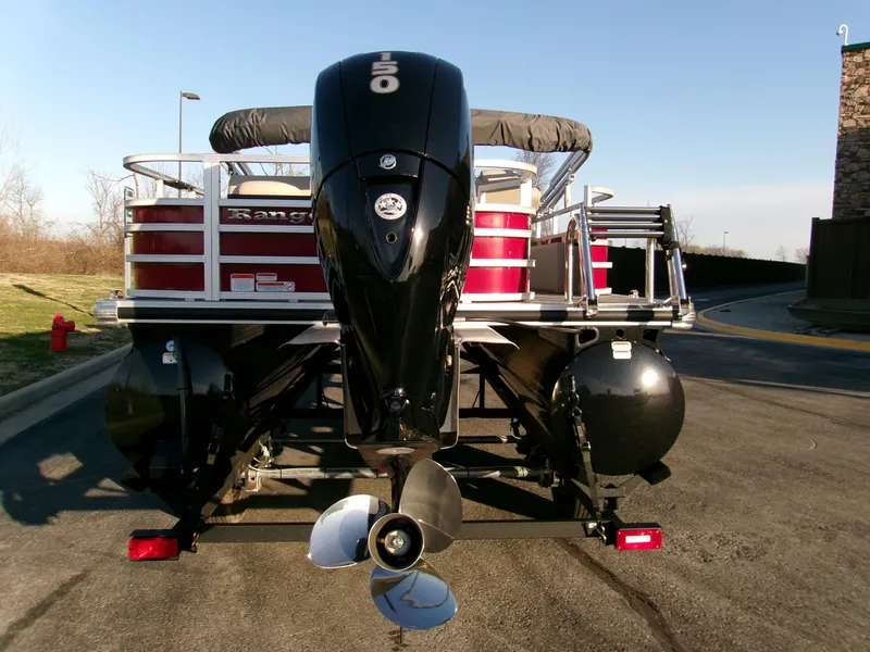 Slide: The Image of 2024 Ranger Reata 220F pontoon boat with powerful outboard motor, parked on a sunny day. - 2