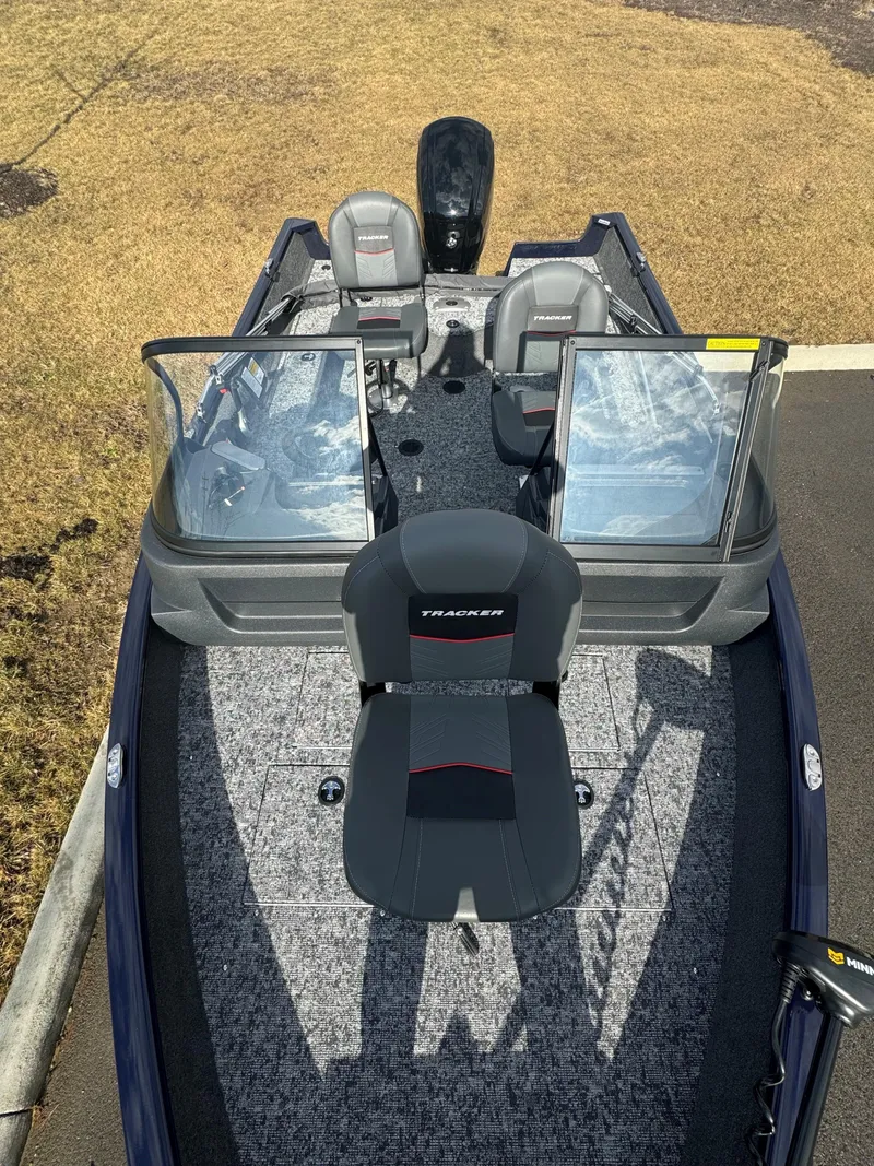 Slide: The Image of 2025 Tracker Pro Guide V-16 WT boat with seating and windshield, parked on grass. - 3