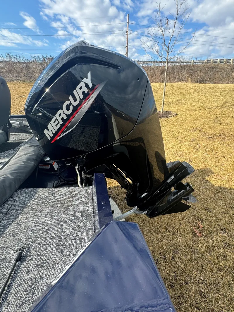 Slide: The Image of 2025 Tracker Pro Guide V-16 WT with Mercury outboard motor, parked on grass under blue sky. - 6