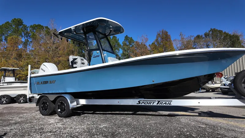 Slide: The Image of 2025 Blazer 2440 boat on Sport Trail trailer, blue hull, parked outdoors. - 11