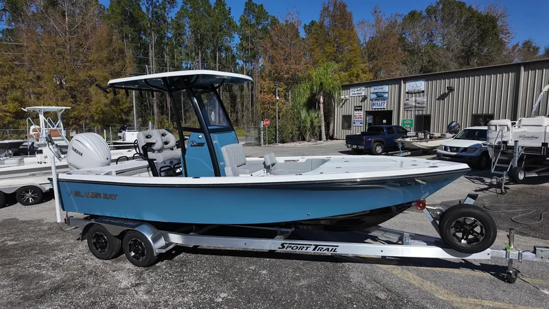 Slide: The Image of 2025 Blazer 2440 boat on Sport Trail trailer, parked outdoors near trees and buildings. - 12