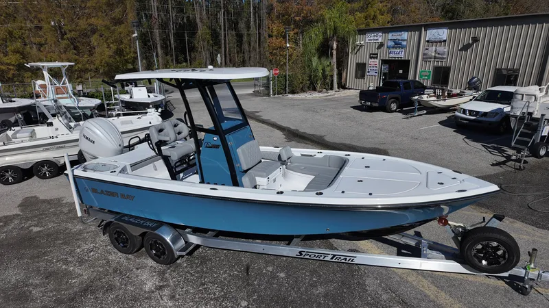 Slide: The Image of 2025 Blazer 2440 boat on trailer at dealership, surrounded by other boats and vehicles. - 13