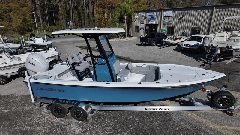 Slide: The Image of 2025 Blazer 2440 boat on trailer, blue and white design, parked outdoors. - 14
