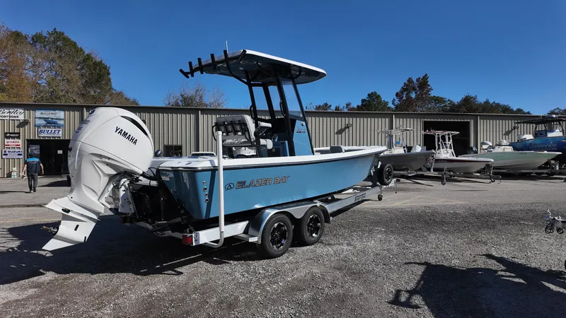 Slide: The Image of 2025 Blazer 2440 boat with Yamaha engine on trailer, parked outside dealership. - 18