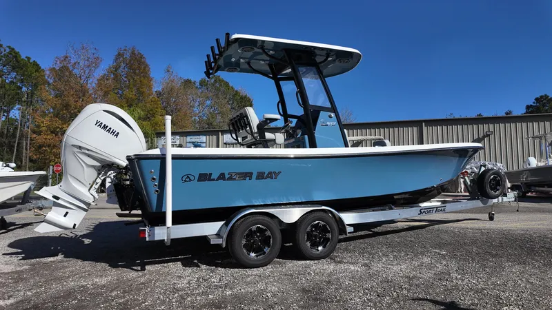 Slide: The Image of 2025 Blazer 2440 boat with Yamaha engine on trailer, parked outdoors. - 2