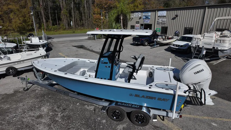 Slide: The Image of 2025 Blazer 2440 boat on trailer, blue and white design, parked outdoors. - 37