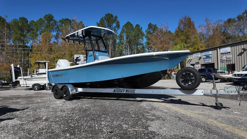 Slide: The Image of 2025 Blazer 2440 boat on trailer, parked outdoors, surrounded by trees and buildings. - 7