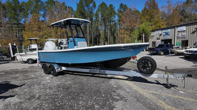 Slide: The Image of 2025 Blazer 2440 boat on trailer, parked outdoors, surrounded by trees and buildings. - 8