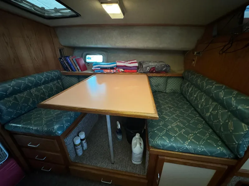 Slide: The Image of 1986 Silverton 34 Convertible interior with dining area, teal cushions, and storage. - 13