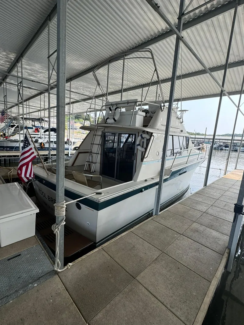 Slide: The Image of 1986 Silverton 34 Convertible boat docked under a covered marina with American flag. - 2