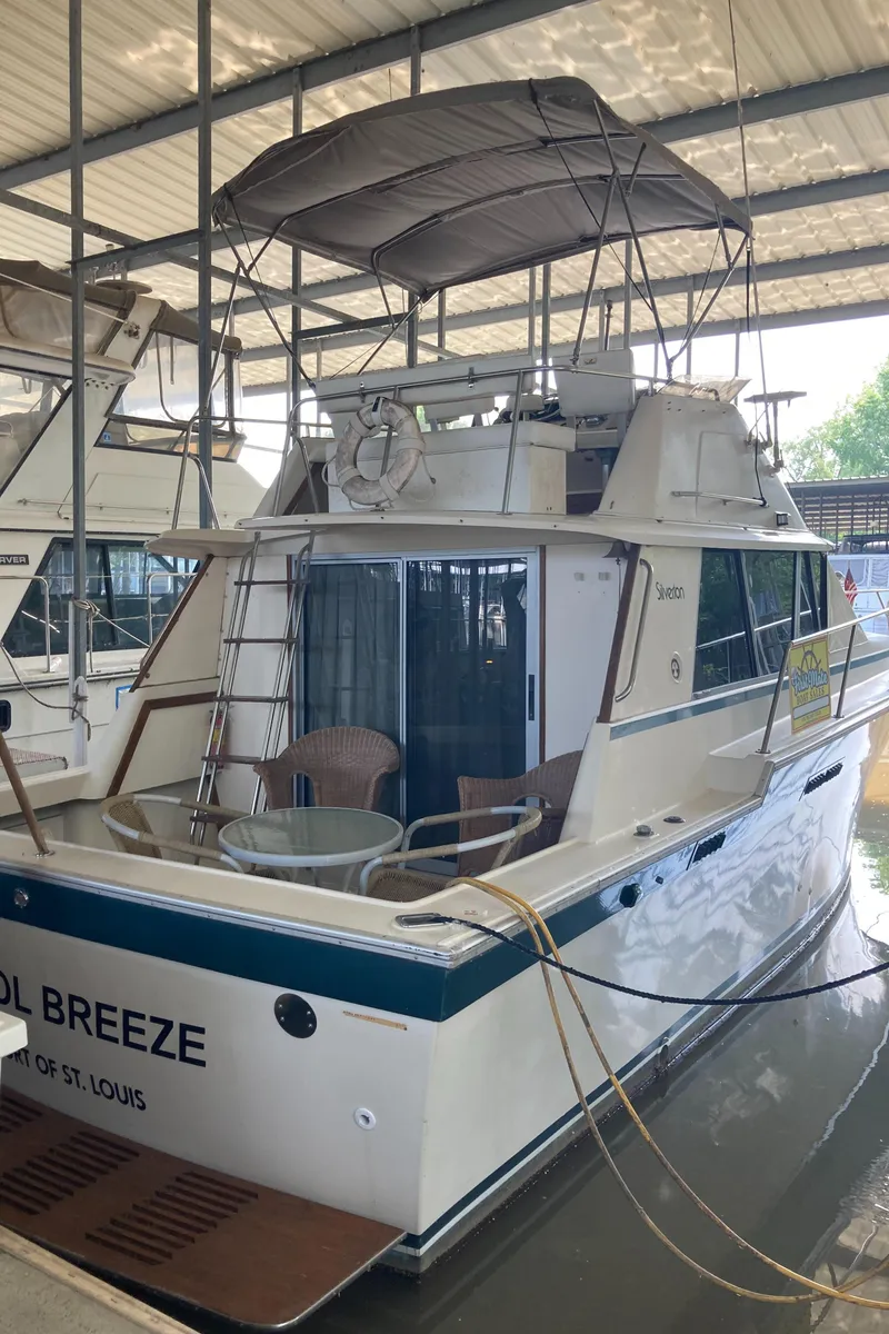 Slide: The Image of 1986 Silverton 34 Convertible boat docked, featuring a covered upper deck and outdoor seating. - 5