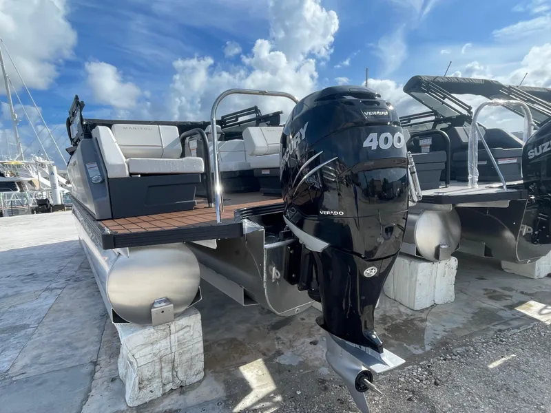 Slide: The Image of 2025 Manitou 26 Explore Switchback pontoon boat with powerful 400 HP outboard motor, docked under blue sky. - 5