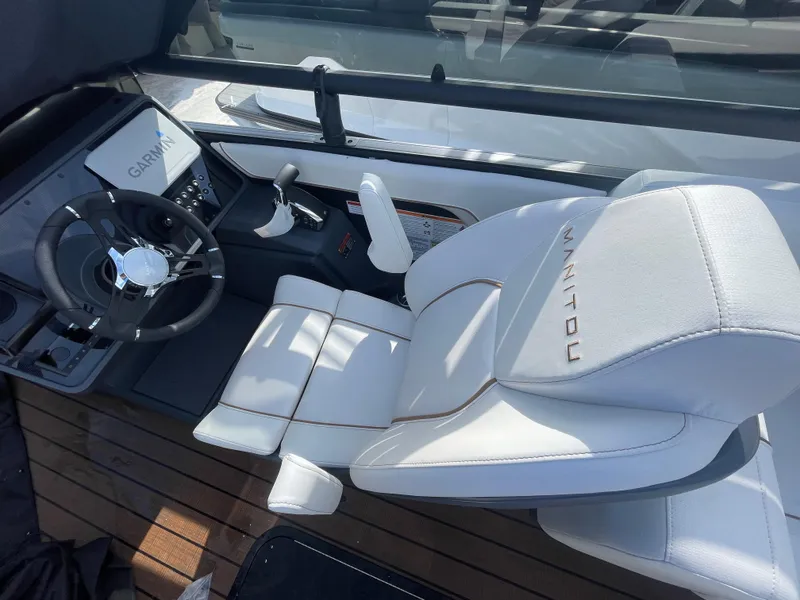 Slide: The Image of Interior of 2025 Manitou 26 Explore Switchback boat with white seating and Garmin navigation. - 8