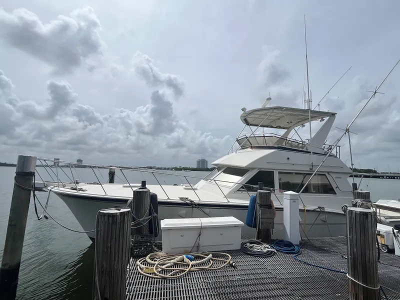 Slide: The Image of 1985 Hatteras 45 Convertible yacht docked at marina under cloudy sky. - 13