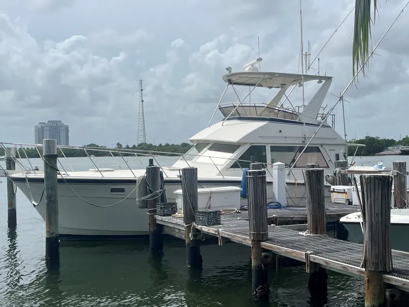 Slide: The Image of 1985 Hatteras 45 Convertible yacht docked at marina under cloudy sky. - 14