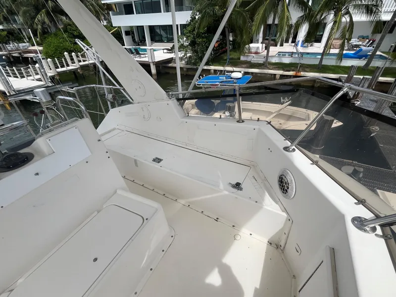 Slide: The Image of 1985 Hatteras 45 Convertible yacht deck with seating, docked near waterfront homes. - 28