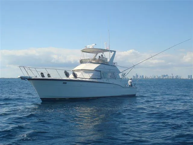 Slide: The Image of 1985 Hatteras 45 Convertible yacht on open sea with city skyline. - 4