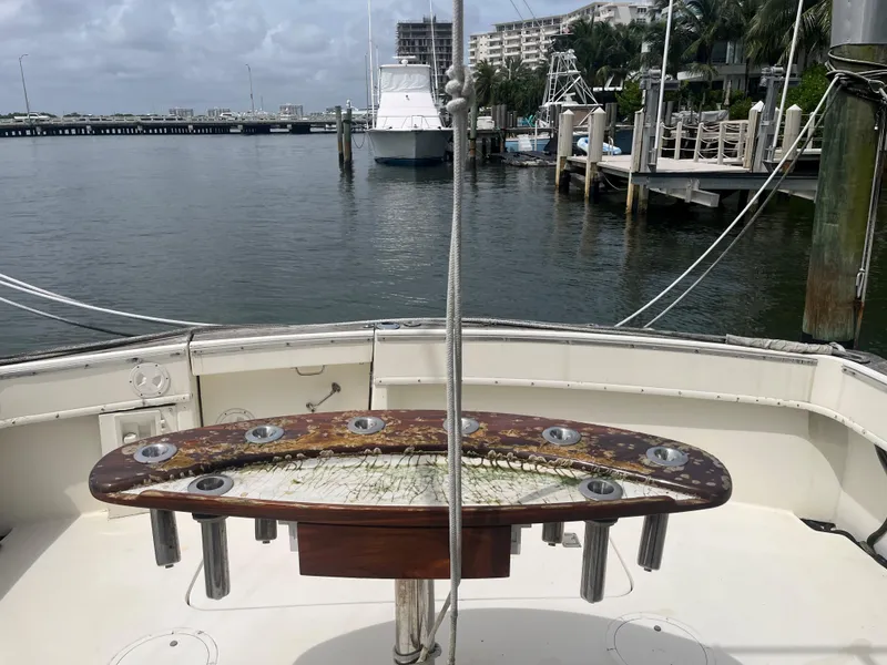 Slide: The Image of 1985 Hatteras 45 Convertible yacht docked at marina, featuring fishing rod holders. - 48