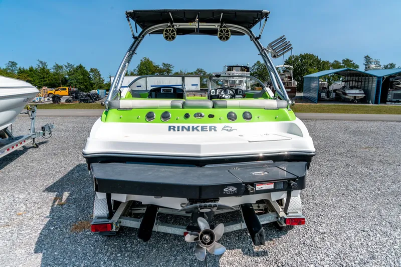 Slide: The Image of 2014 Rinker Captiva 200 MTX boat, rear view, parked on gravel, with green accents. - 7